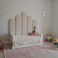 Children's bed with unique headboard design in a room with toys and a rug.