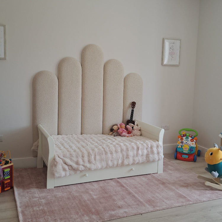 Children's bed with unique headboard design in a room with toys and a rug.