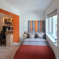 Small room with an upholstered headboard in a bedroom with desk, and chair.