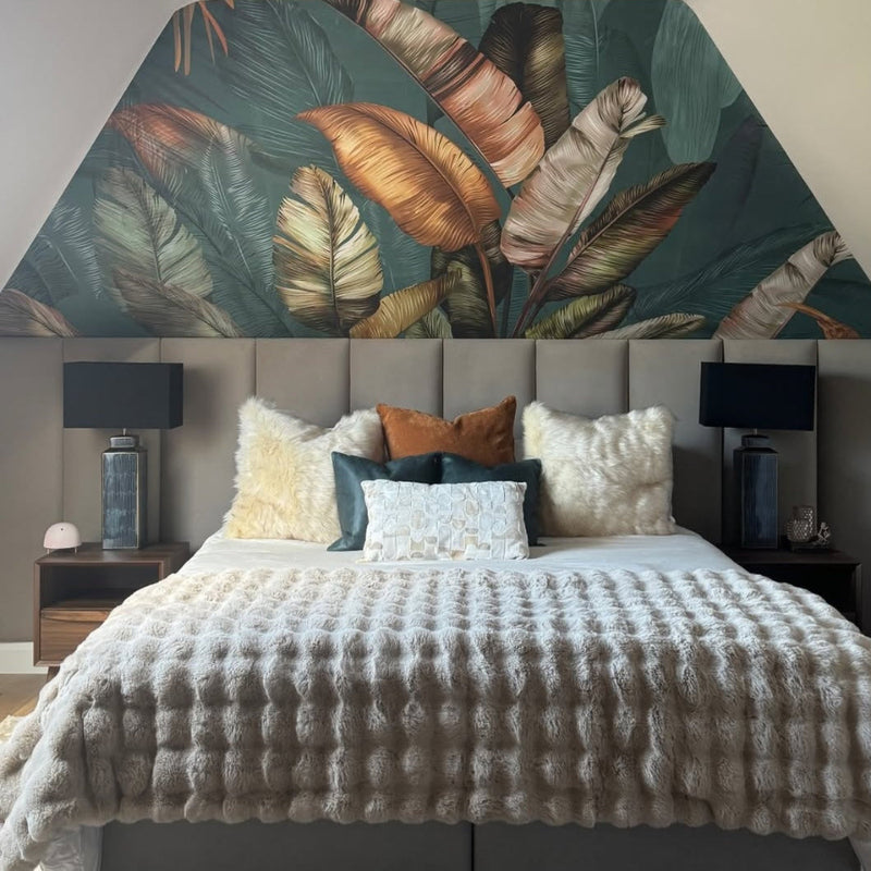 Modern bedroom with a bed, decorative pillows, and leaf-patterned wall. Set in front of grey upholstered wall panels