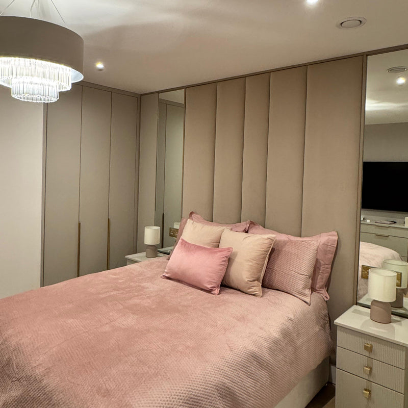 Neatly made bed with pink bedding in a modern upholstered wall panels