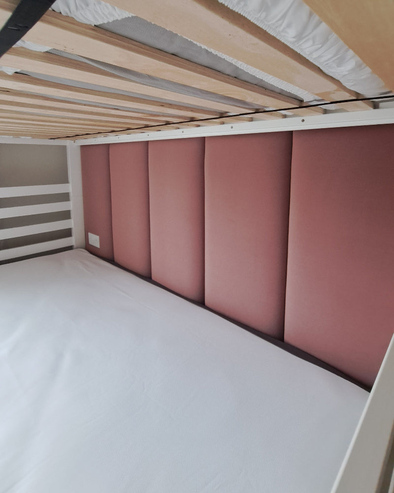 Bunk bed with pink upholstered wall panel and white mattress