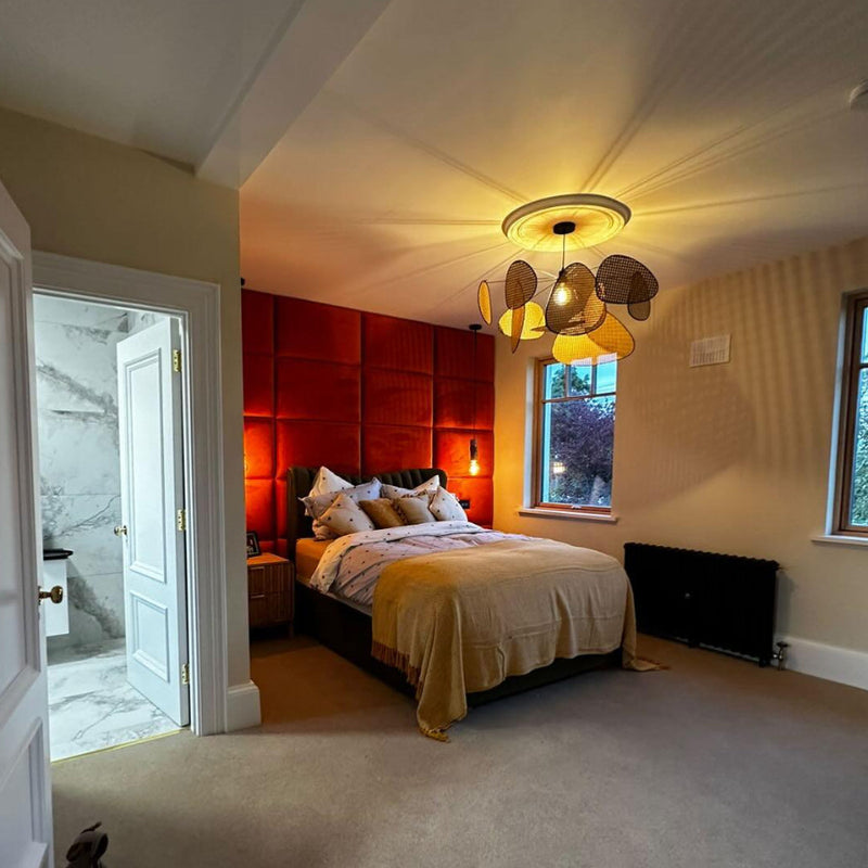 Modern bedroom with red accent wall featuring red upholstered wall panels, bed, and ceiling light fixture.